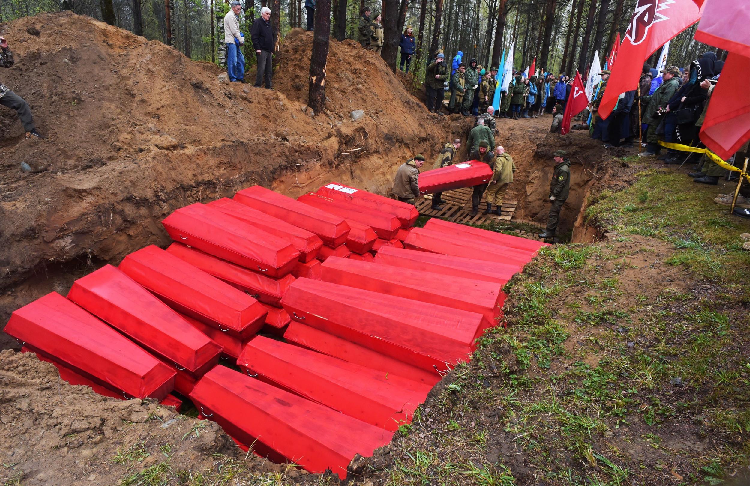 Members of volunteer search groups place a coffin with the remains of Red Army soldiers killed in the Second World War into a mass grave during a reburial ceremony at the Sinyavino Heights memorial site outside Saint Petersburg (AFP via Getty)