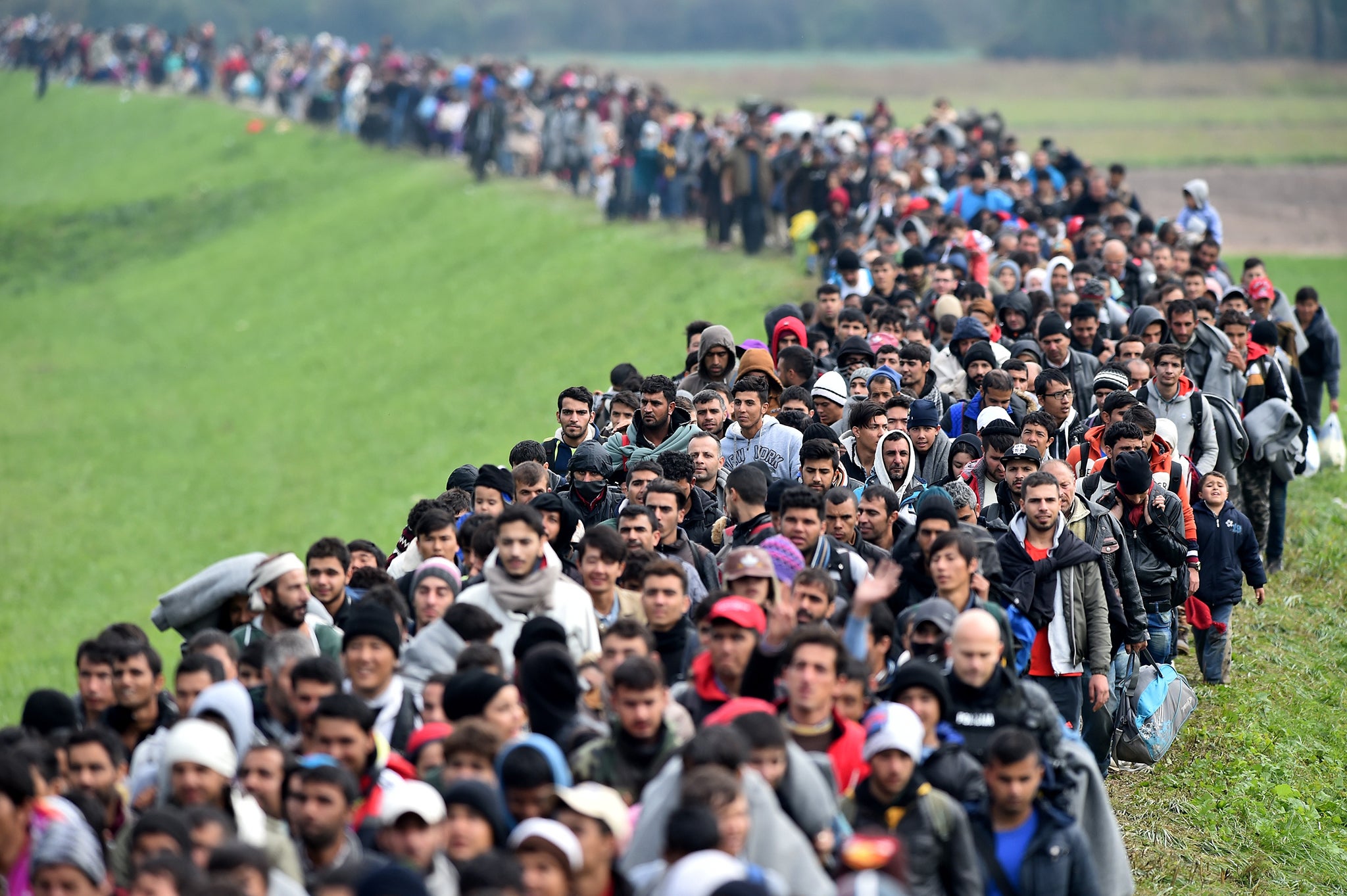 Migrants are escorted through fields by police from the village of Rigonce to Brezice refugee camp in Slovenia