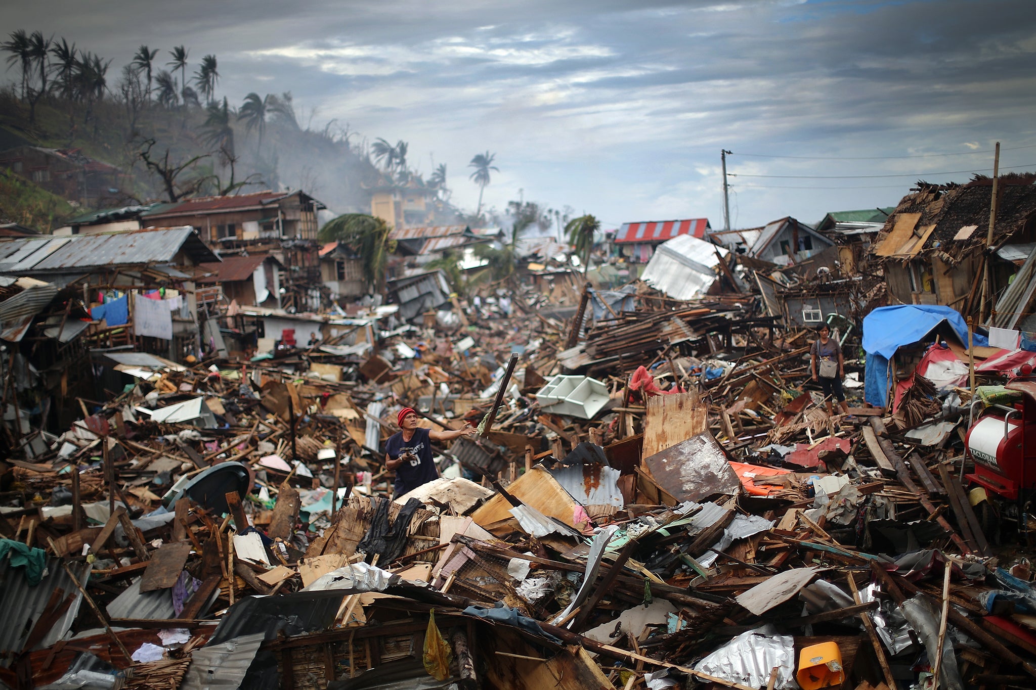 A man sifts through debris in what was a river running through central Tacloban after Typhoon Haiyan