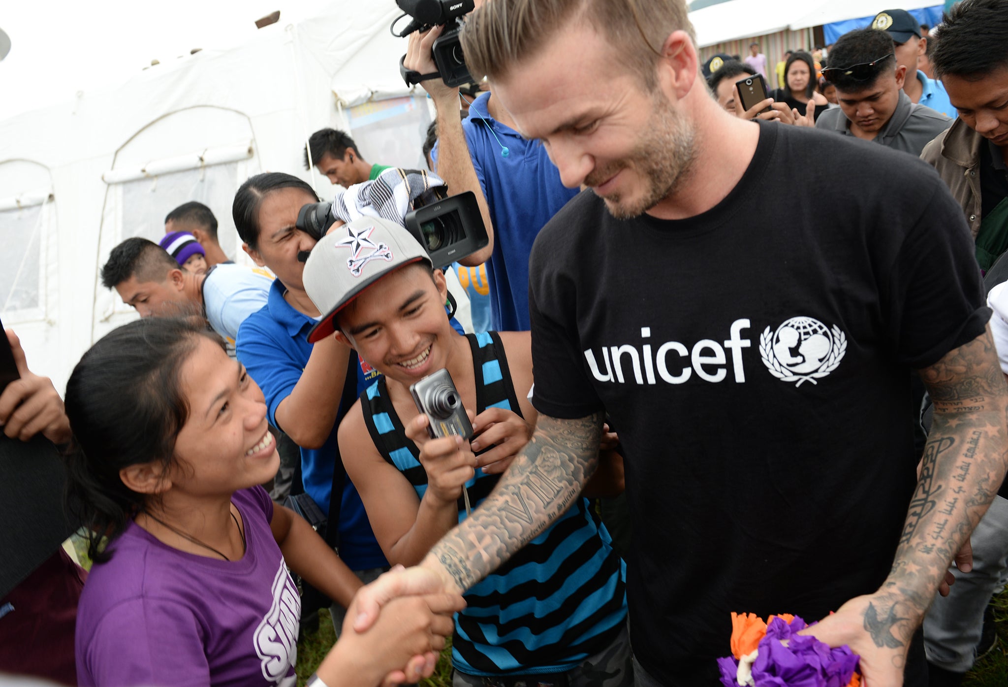 David Beckham greets survivors of Typhoon Haiyan during a visit to a tent city in Tacloban