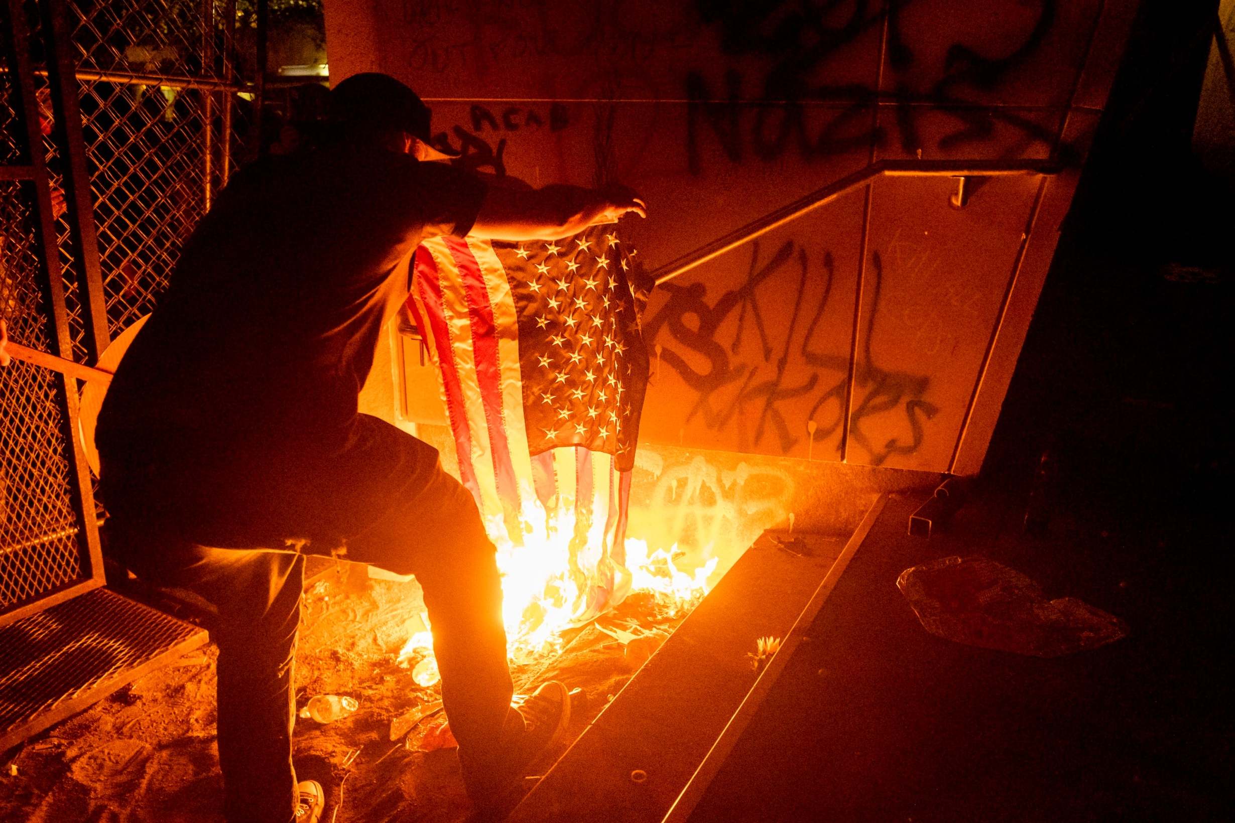 A Black Lives Matter protester burns an American flag outside the Mark O. Hatfield United States Courthouse in July 2020