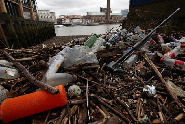 Plastic bottles and other waste litter the shore of the River Thames at Queenhithe Dock, London.
