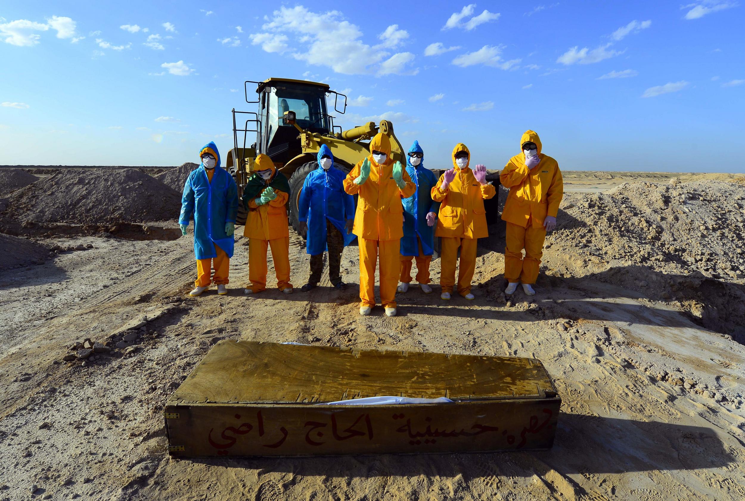 Volunteers in full hazmat gear pray over the coffin of a 50-year-old Covid-19 victim before her burial at the cemetery (AFP/Getty)