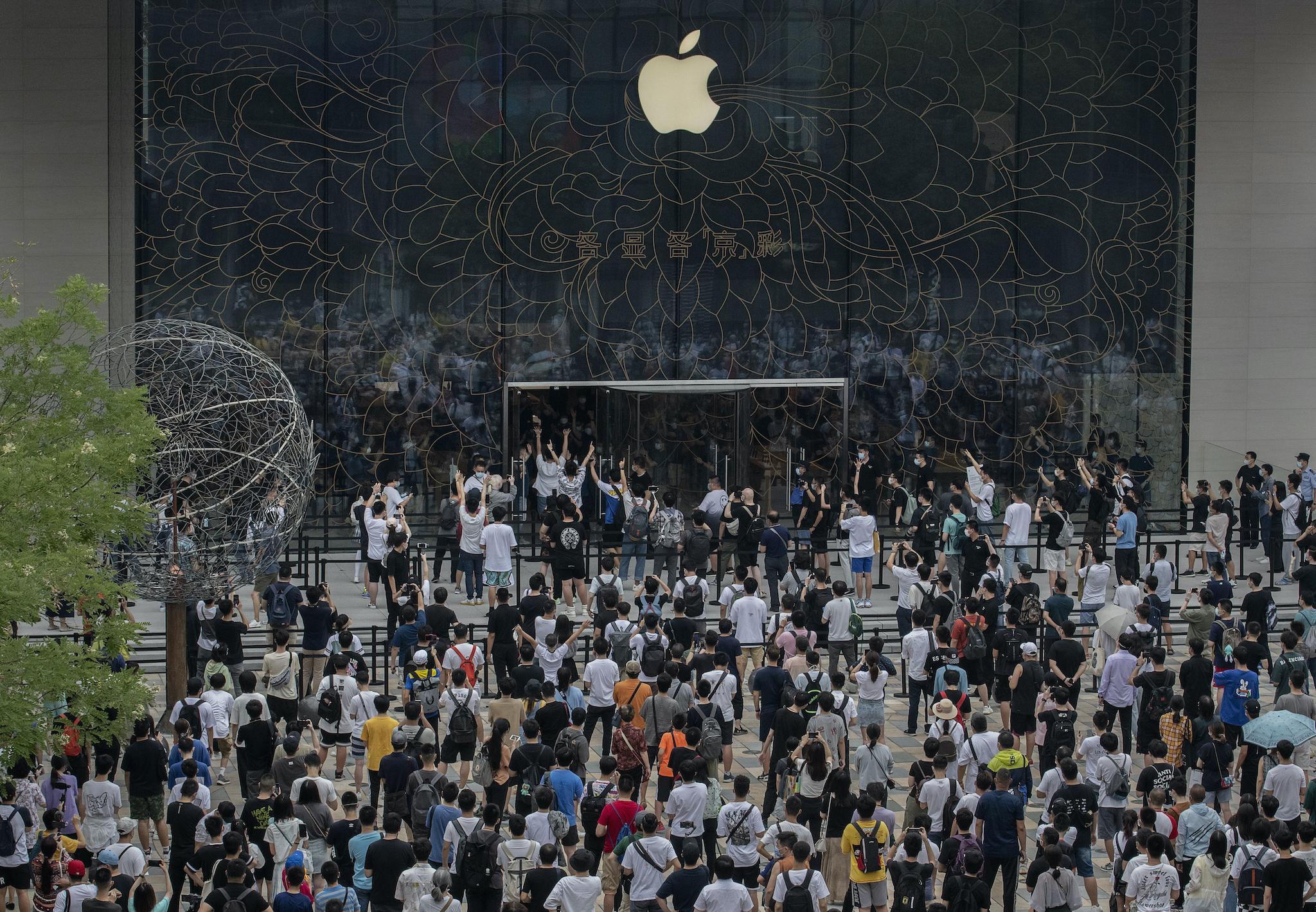 People wait in line following social distancing rules as others enter during the official opening of the new Apple Store in the Sanlitun shopping area on July 17, 2020 in Beijing, China