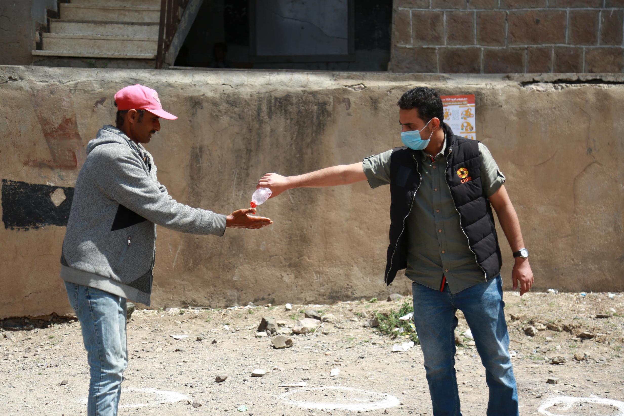 An aid worker in Ibb gives a man some hand sanitiser