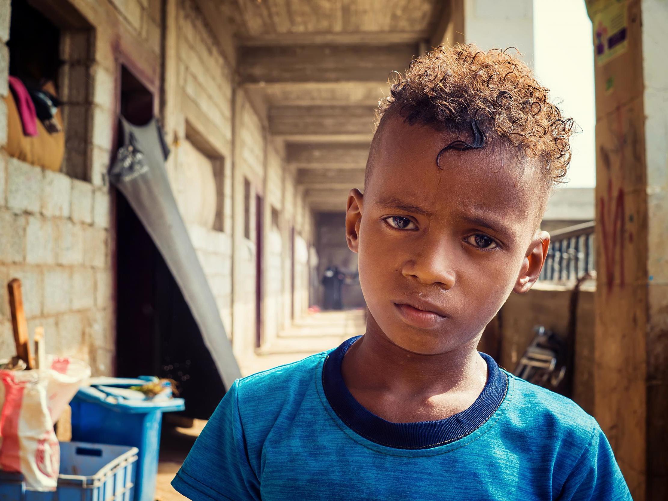 A boy stands in the unfinished school next to the camp where he lives, near Aden