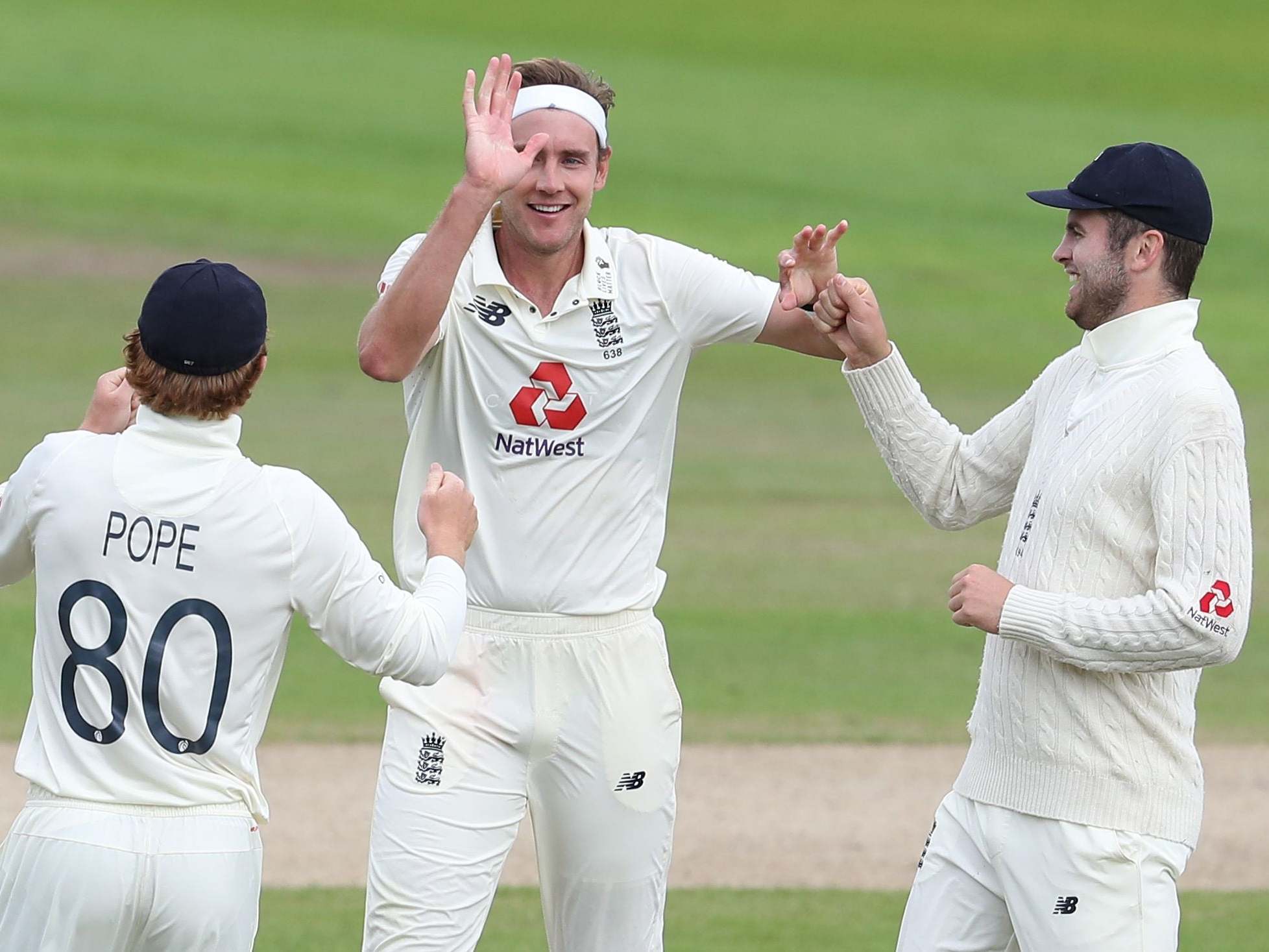 Stuart Broad celebrates with teammates after taking the wicket of West Indies' Roston Chase