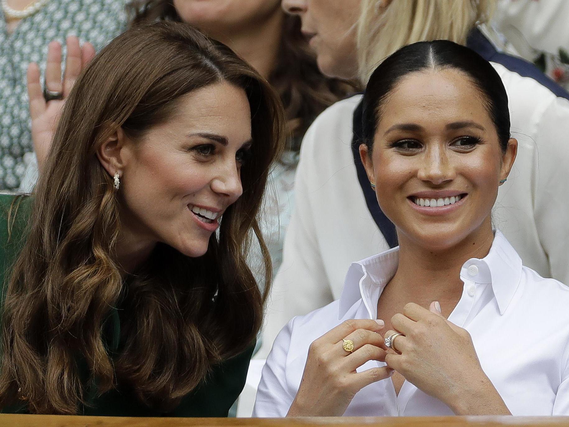 Kate, Duchess of Cambridge, left, and Meghan, Duchess of Sussex chat as they sit in the Royal Box on Centre Court to watch the women's singles final match between Serena Williams of the United States and Romania's Simona Halep on day twelve of the Wimbledon Tennis Championships in London.