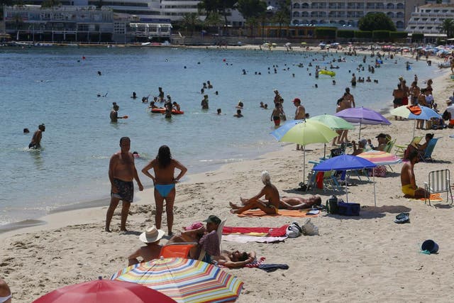People enjoy Magaluf beach in Mallorca. Britons are surprised at the abrupt announcement to impose a two-week quarantine on people travelling to the UK from Spain