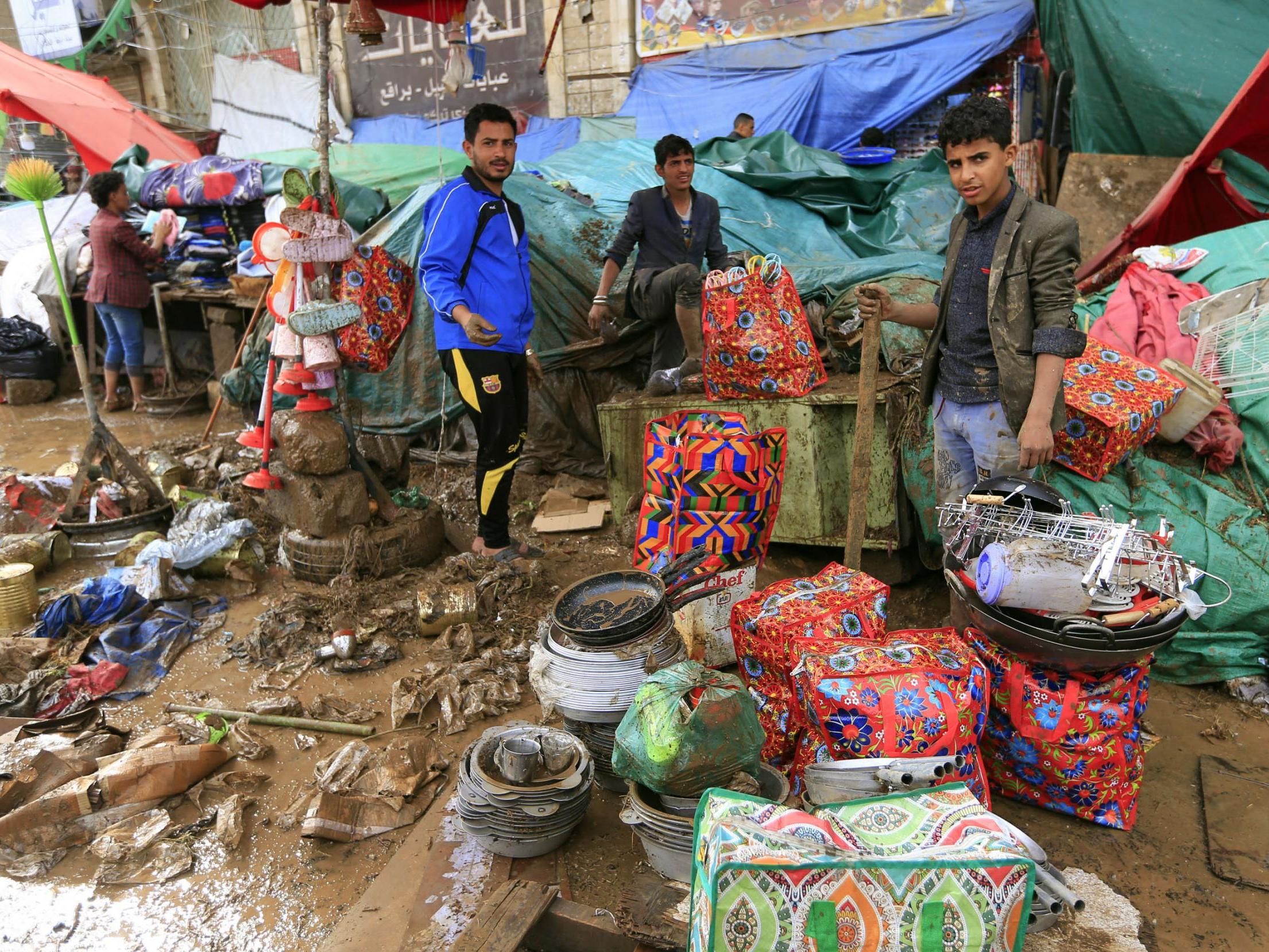 Yemenis salvage goods from a damaged vendor stall, flooded with mud following heavy rains in the capital Sanaa