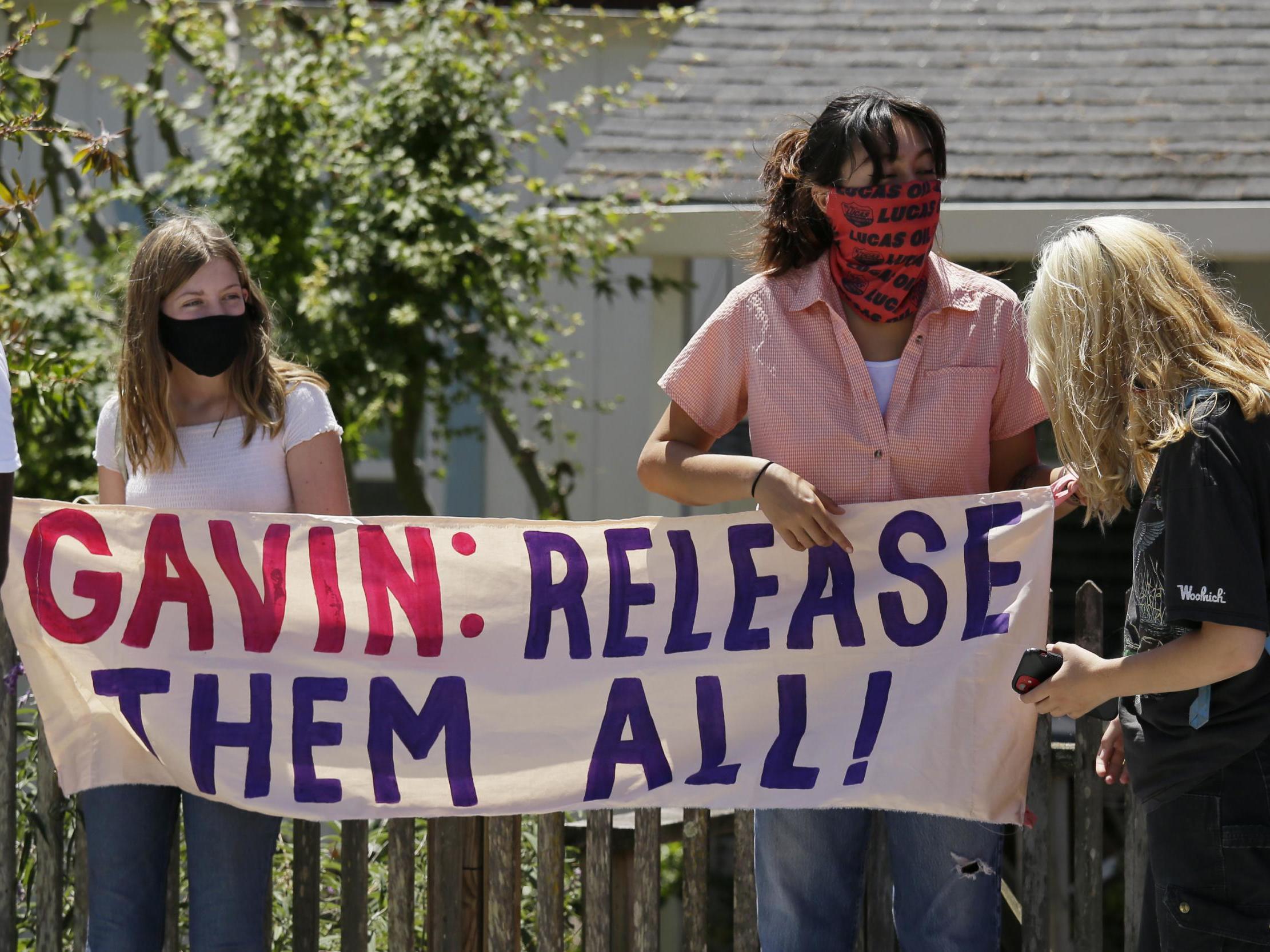 Two women hold up a banner before the start of a news conference urging California Gov Gavin Newsom to release prisoners