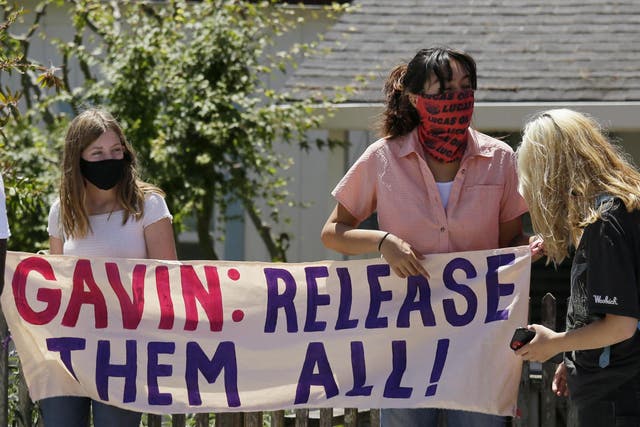 Two women hold up a banner before the start of a news conference urging California Gov Gavin Newsom to release prisoners