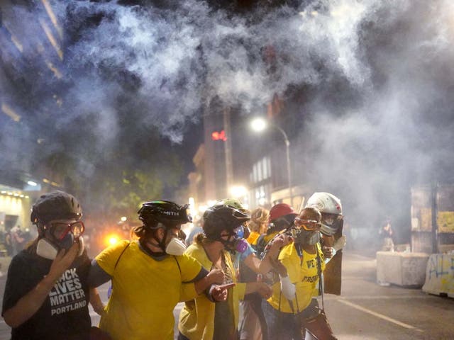 Members of Moms United for Black Lives Matter brace themselves against tear gas fired by federal officers in Portland, Oregon