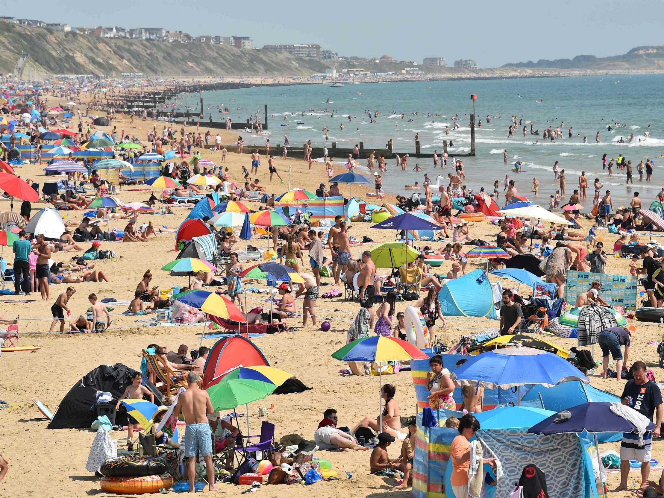 Beachgoers enjoy the sunshine as they sunbathe and play in the sea on Bournemouth beach in Bournemouth