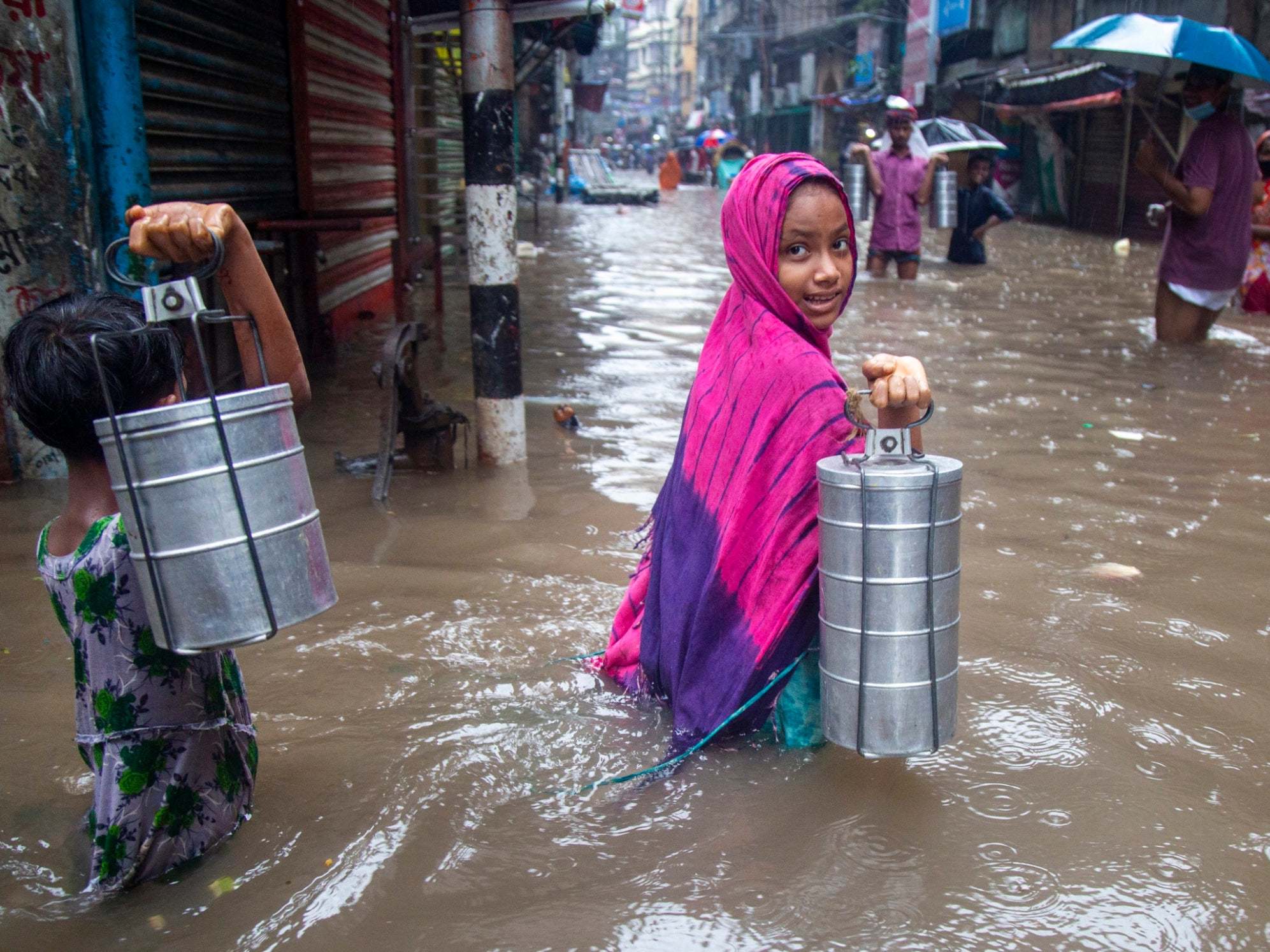 Children carrying tiffin boxes through a flooded street in Dhaka, Bangladesh last week