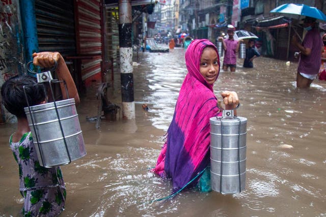 Children carrying tiffin boxes through a flooded street in Dhaka, Bangladesh last week