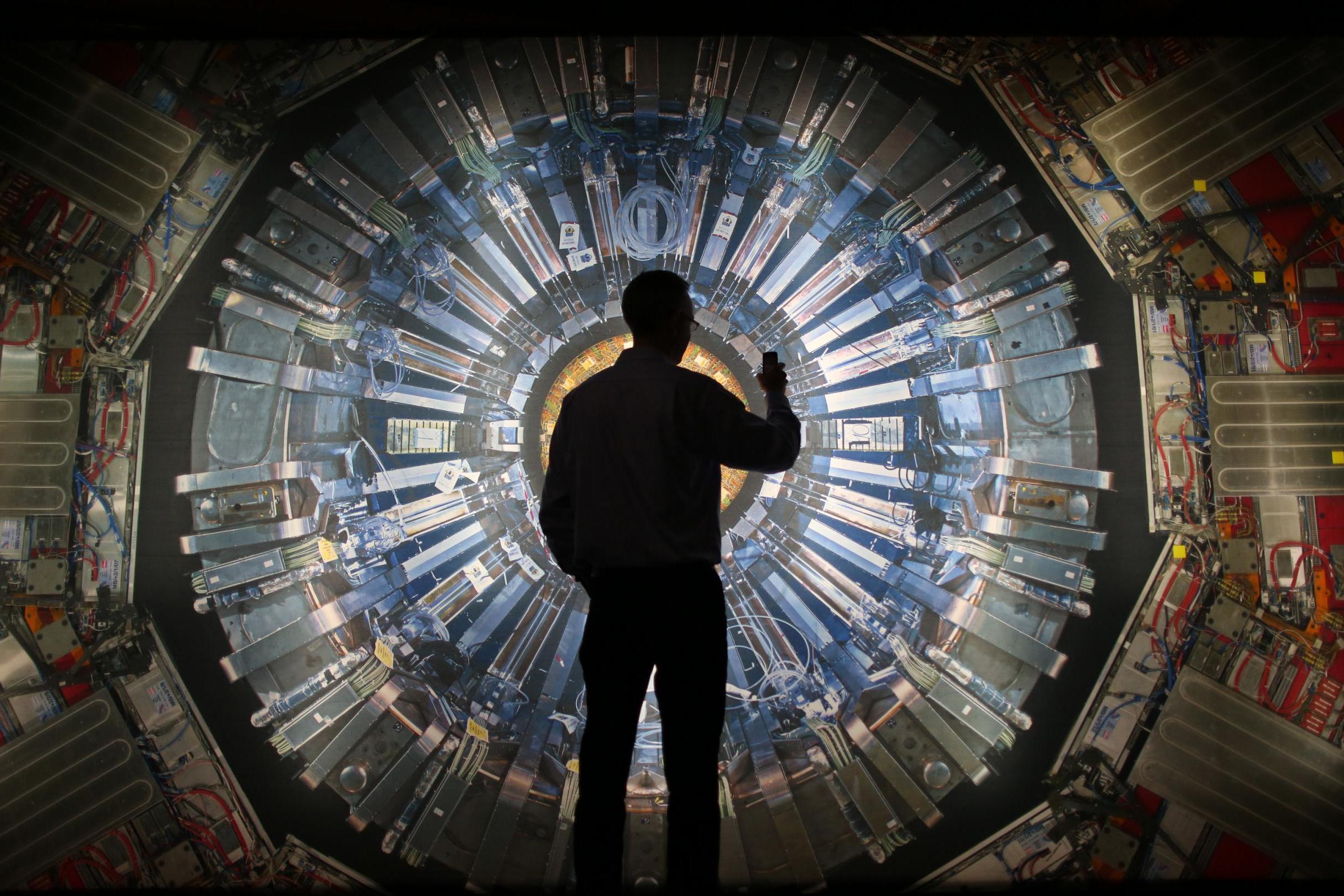 A visitor takes a photo of an image of the Large Hadron Collider at the Science Museum’s ‘Collider’ exhibition in 2013 (Getty)