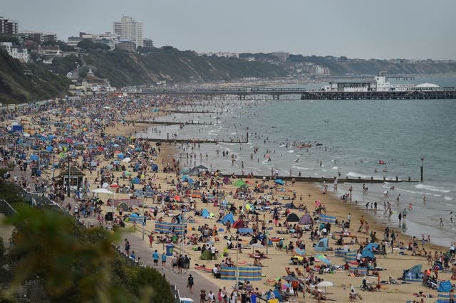 Beachgoers enjoy the sunshine as they sunbathe and play in the sea on Bournemouth beach