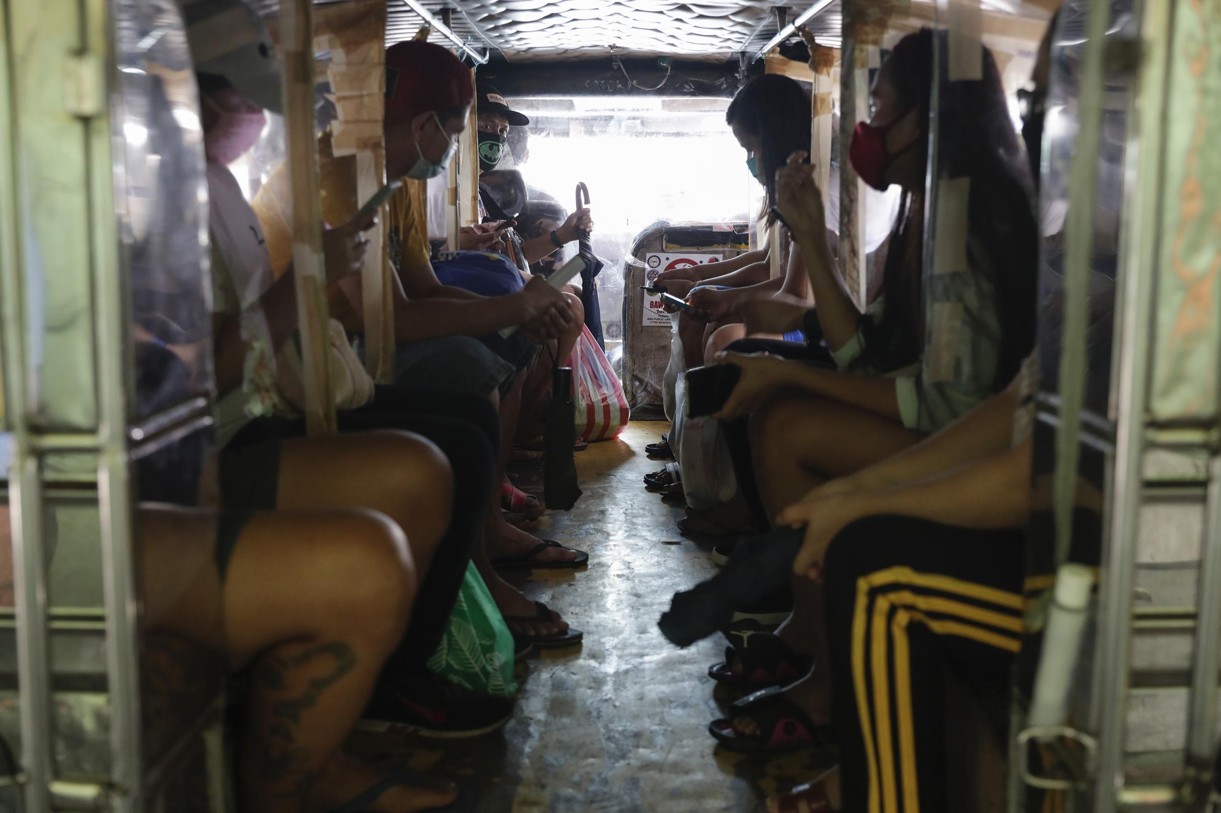 Passengers of a jeepney bus are separated by plastic sheets to help curb the spread of Covid-19