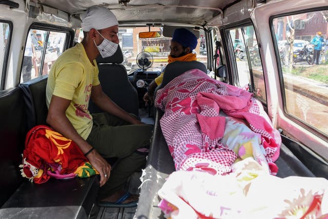 A relative sits near the body of Kirpal Singh, who died after allegedly drinking spurious alcohol, in a vehicle at a civil hospital in Tarn Taran some 25kms from Amritsar