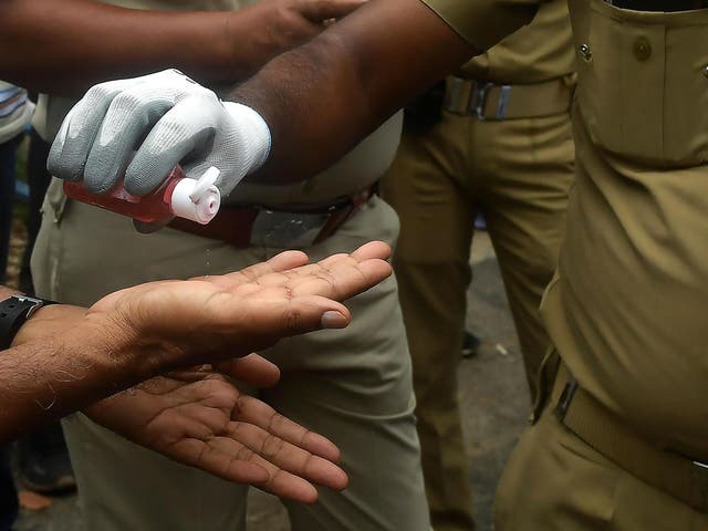 Police officers use hand sanitiser in Kolkata, India, on 27 July, 2020.