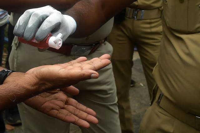 Police officers use hand sanitiser in Kolkata, India, on 27 July, 2020.
