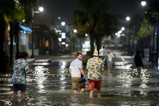 People walk through floodwaters on Ocean Blvd in Myrtle Beach, South Carolina on Monday