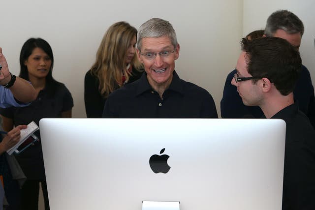 Apple CEO Tim Cook looks at the new 27 inch iMac with 5K retina display during an Apple special event on October 16, 2014 in Cupertino, California