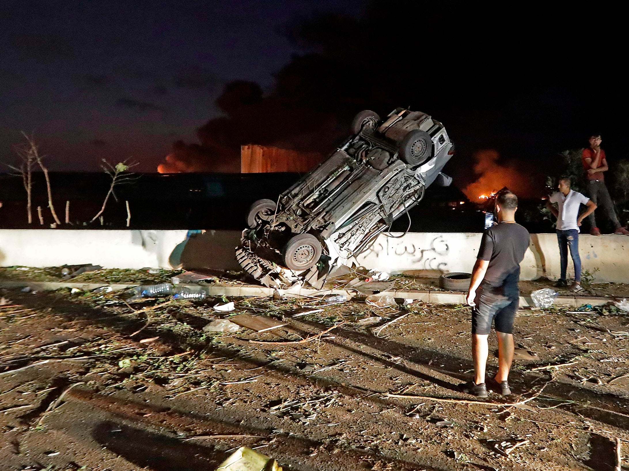 People gather by cars destroyed by the explosion