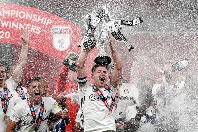 Fulham's Tom Cairney lifts the trophy as he celebrates promotion