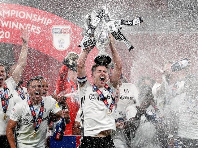 Fulham's Tom Cairney lifts the trophy as he celebrates promotion
