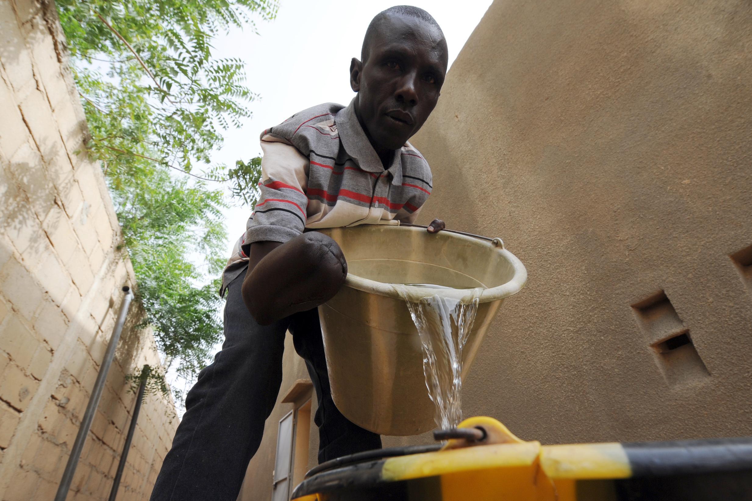 A man amputated for alleged theft by Islamists pours water in Gao, which had been controlled by sharia law until the French intervention