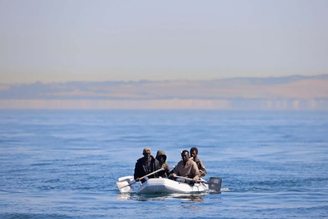 Four men off the coast of France, some using shovels as paddles, use a small dinghy to cross the English Channel on 7 August 2020