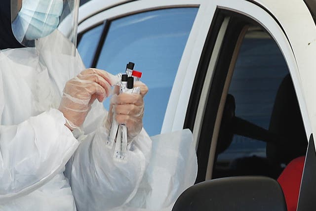 A healthcare worker conducts a coronavirus test at a drive-through testing centre for NHS staff and care workers