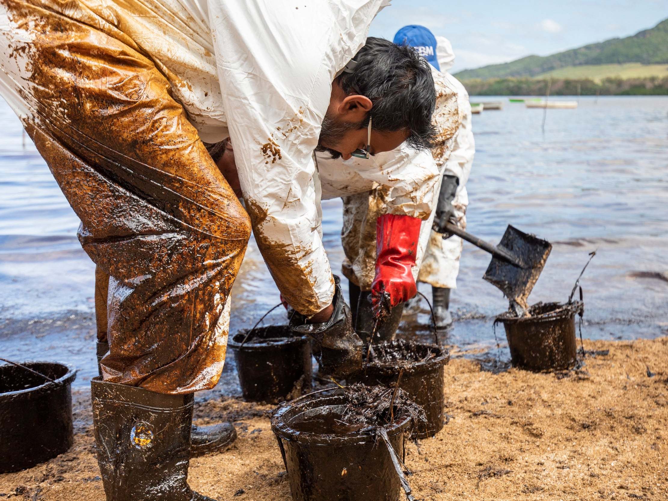Local volunteers clean up oil washing up on the beach from the MV Wakashio