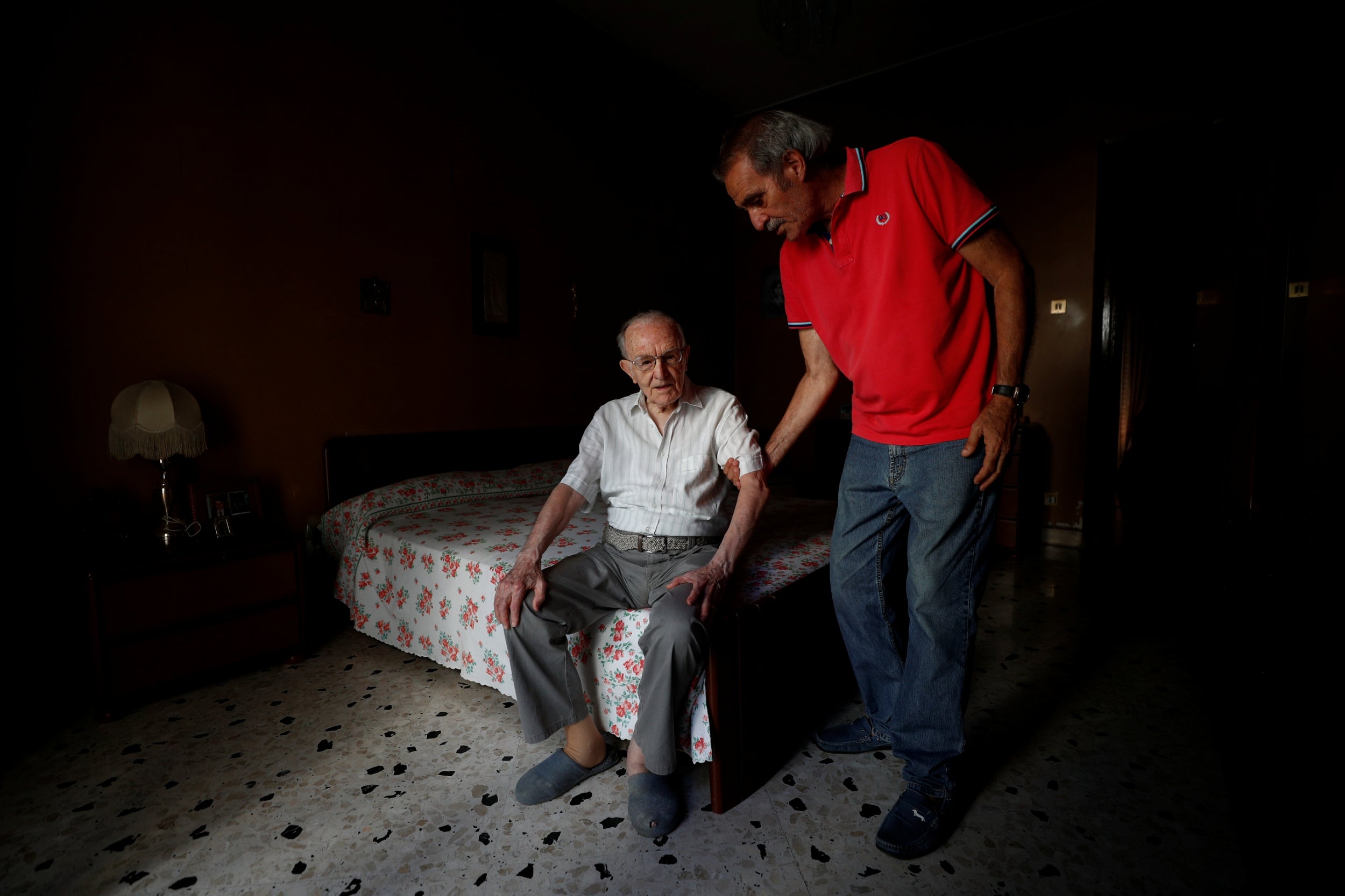 Paterno is helped from his bed by his son Ninni, 72