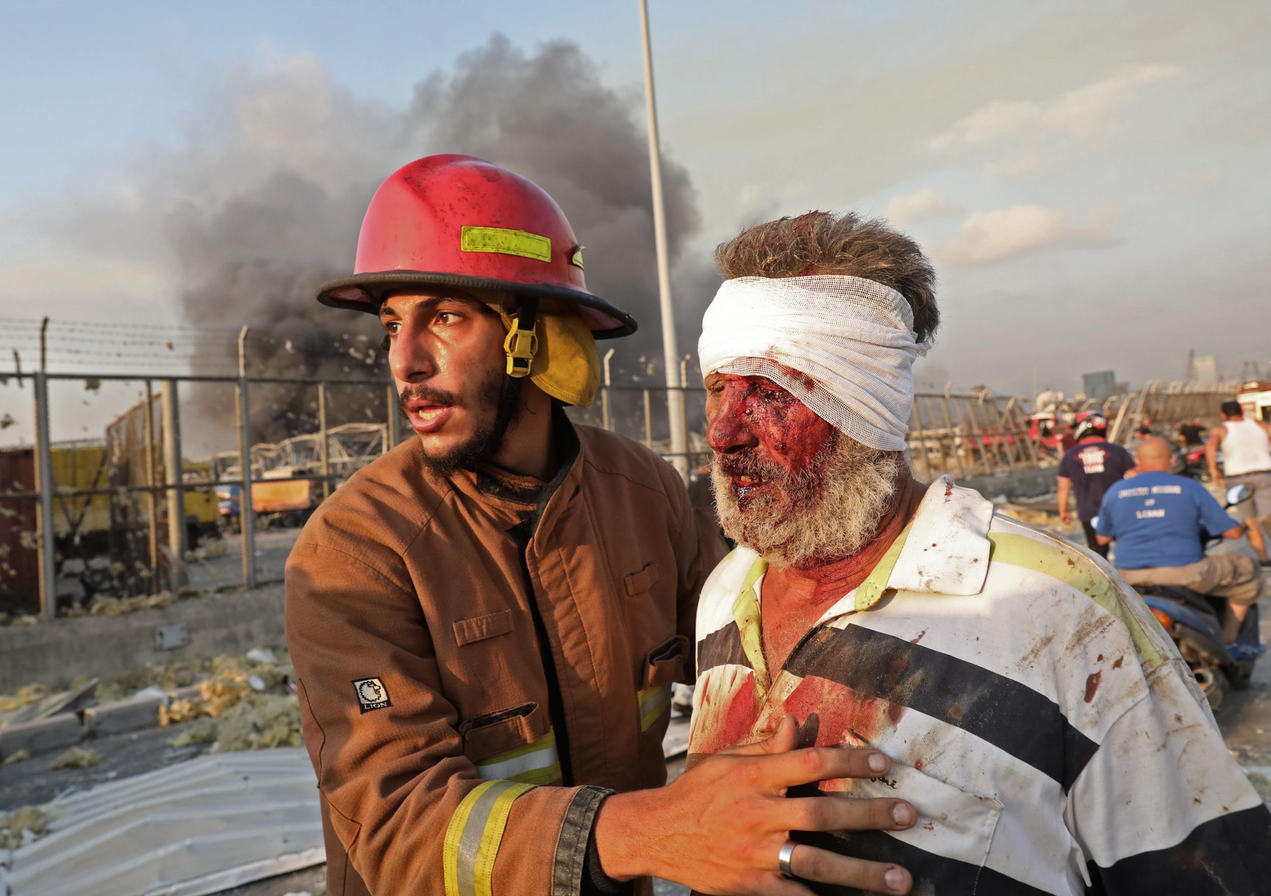 A wounded man is helped by a firefighter near the scene of the explosion in Beirut on 4 August
