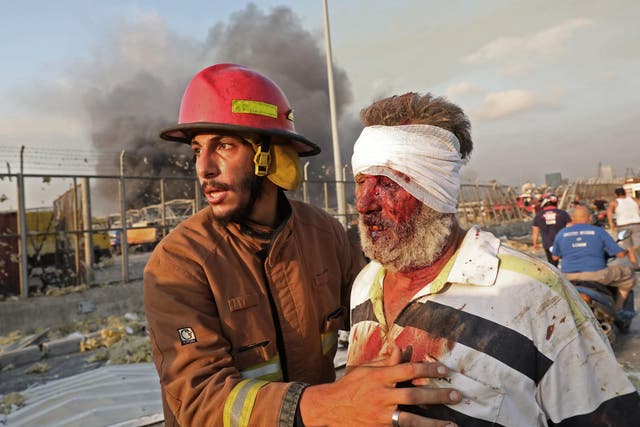 A wounded man is helped by a fireman near the scene of an explosion in Beirut on August 4, 2020