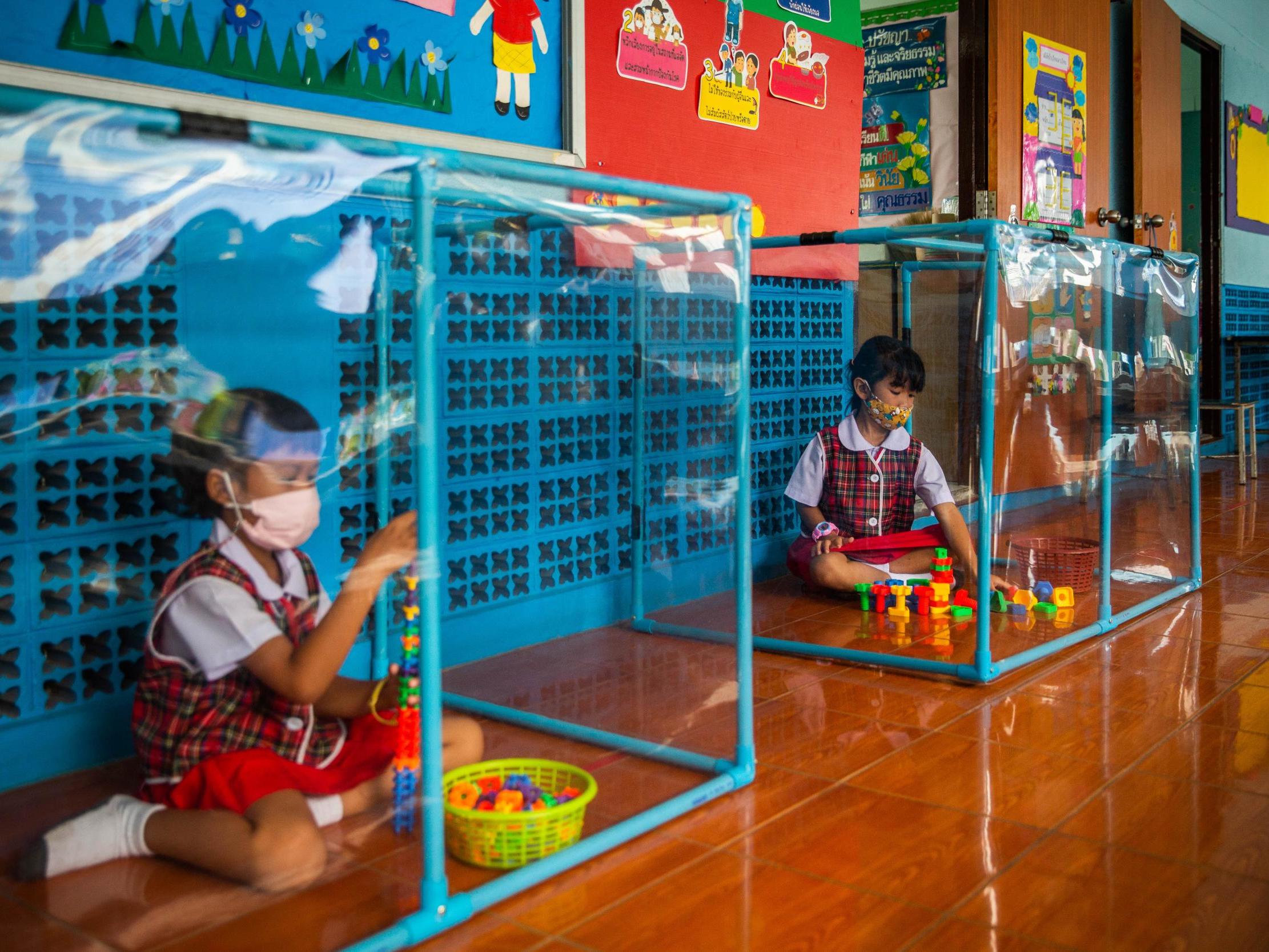 Two Thai pupils play behind plastic screens in separate play areas at the Wat Khlong Toey School on August 10, 2020 in Bangkok, Thailand.