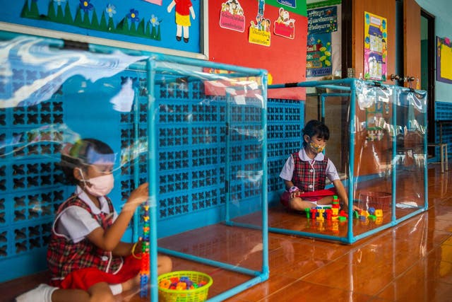 Two Thai pupils play behind plastic screens in separate play areas at the Wat Khlong Toey School on August 10, 2020 in Bangkok, Thailand.