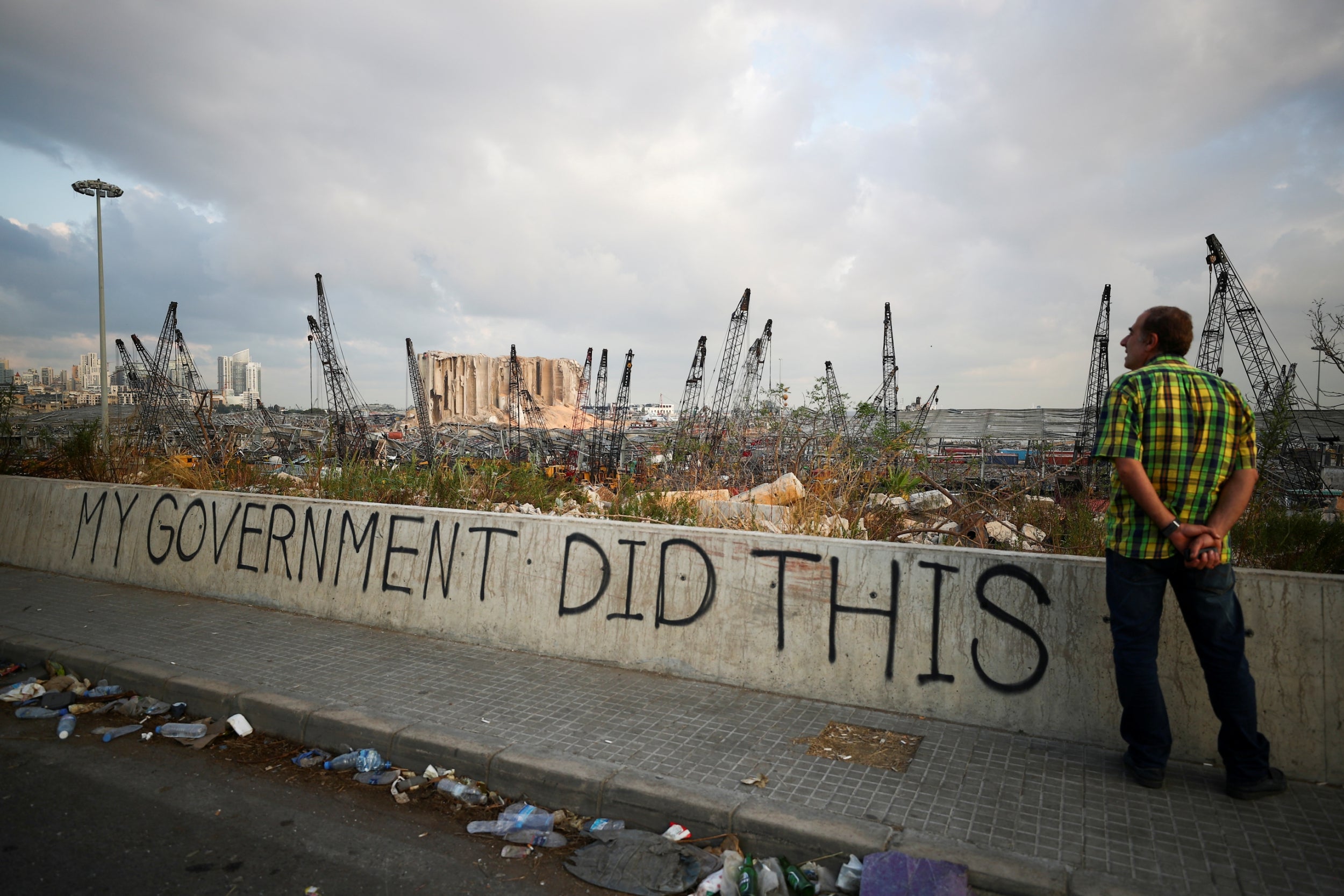 A man stands next to graffiti at the damaged port area in the aftermath of the massive explosion