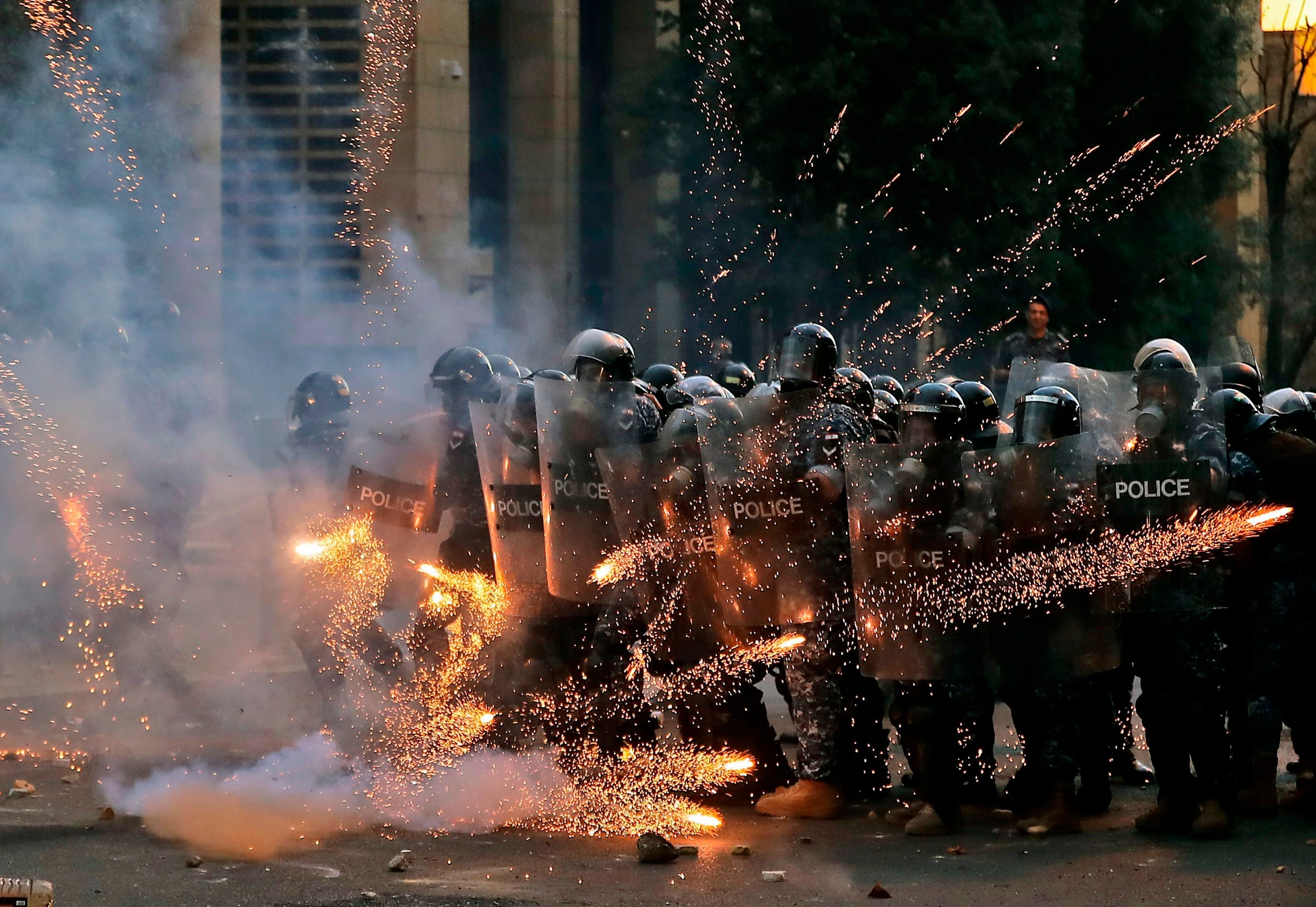 Firecrackers thrown by protesters explode in front of riot police