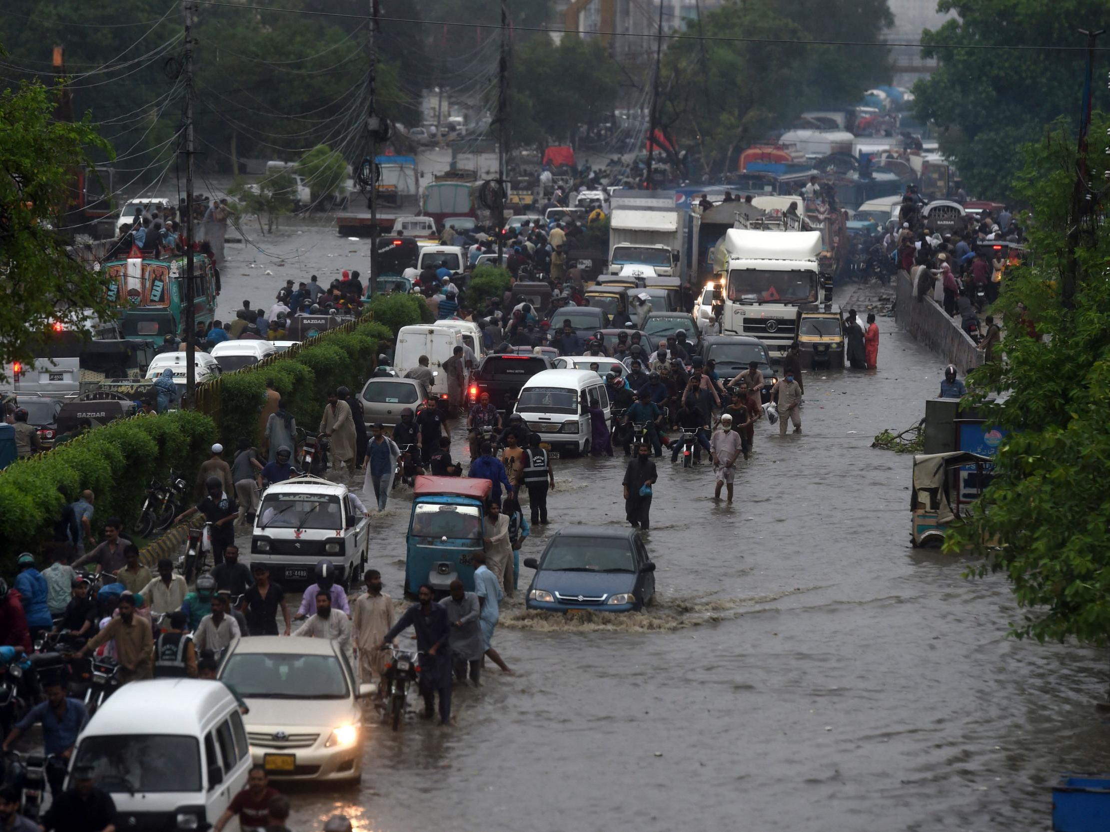 Commuters make their way along a flooded street after heavy monsoon rains in Pakistan's port city of Karachi