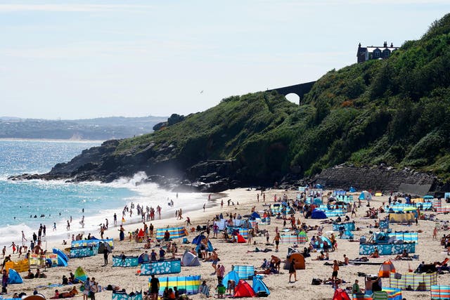 Groups of people relax on the beach in the sun on August 9, 2020 in St Ives, Cornwall, England