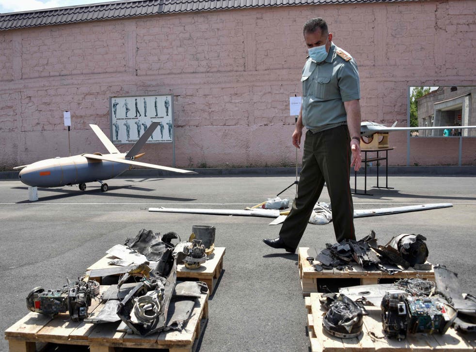 An official walks among objects which Armenia presented as downed drones during recent armed clashes
