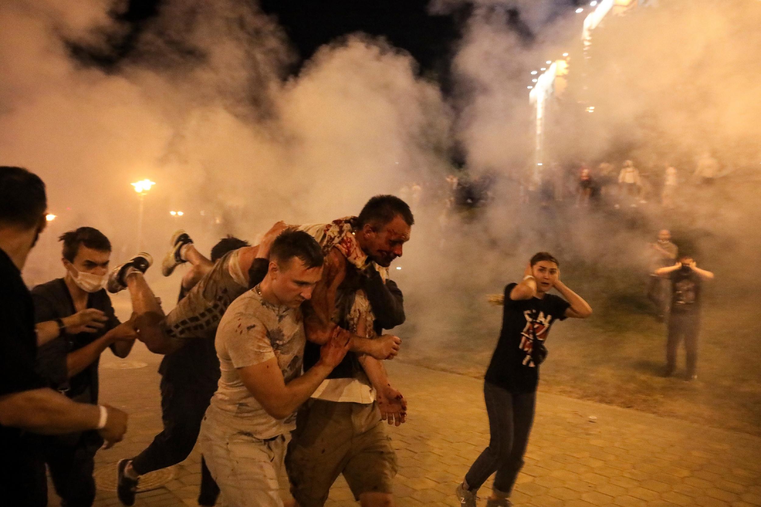 Protesters carry a man wounded during clashes with police