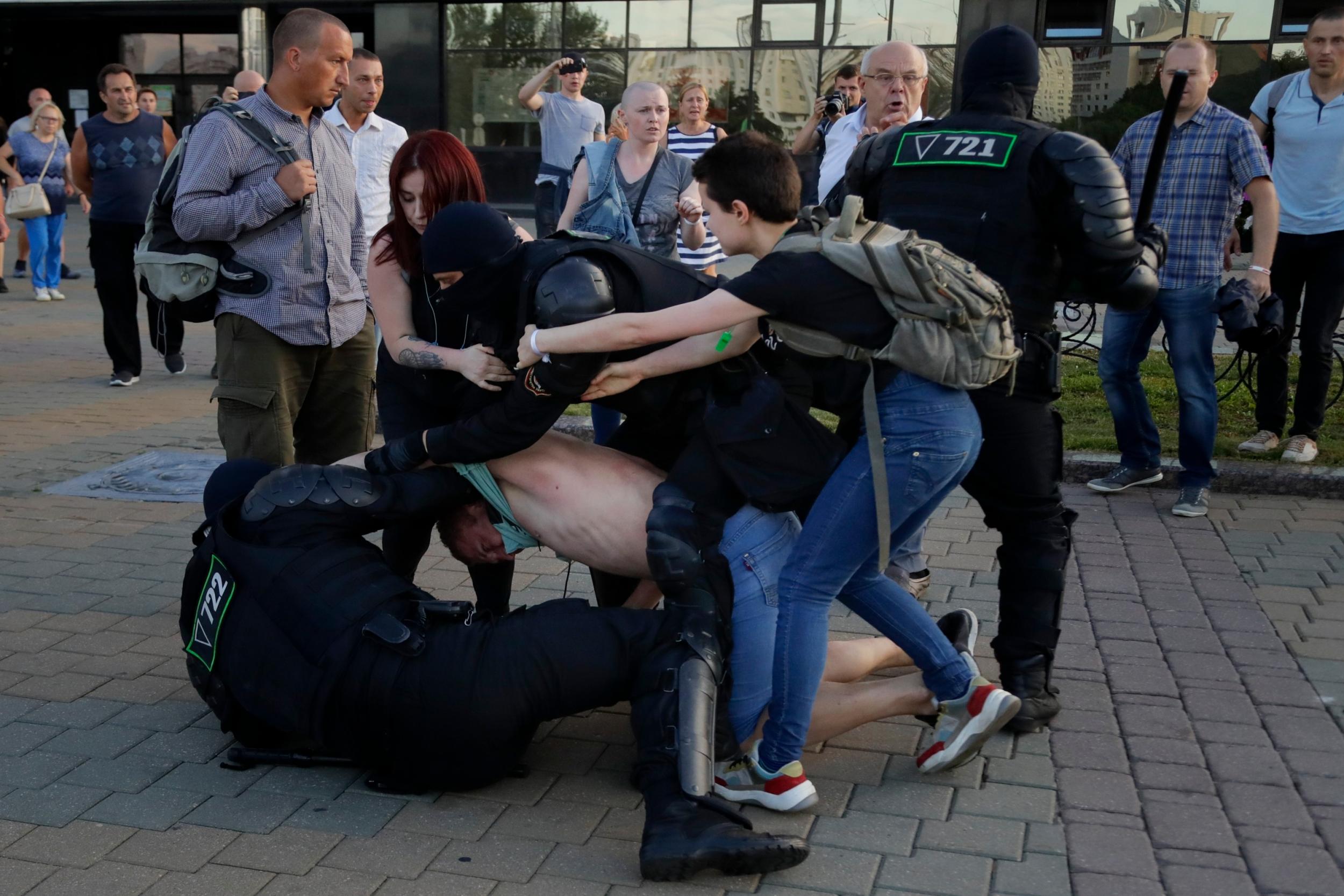 Police detain a protester as two women try to defend him during a demonstration