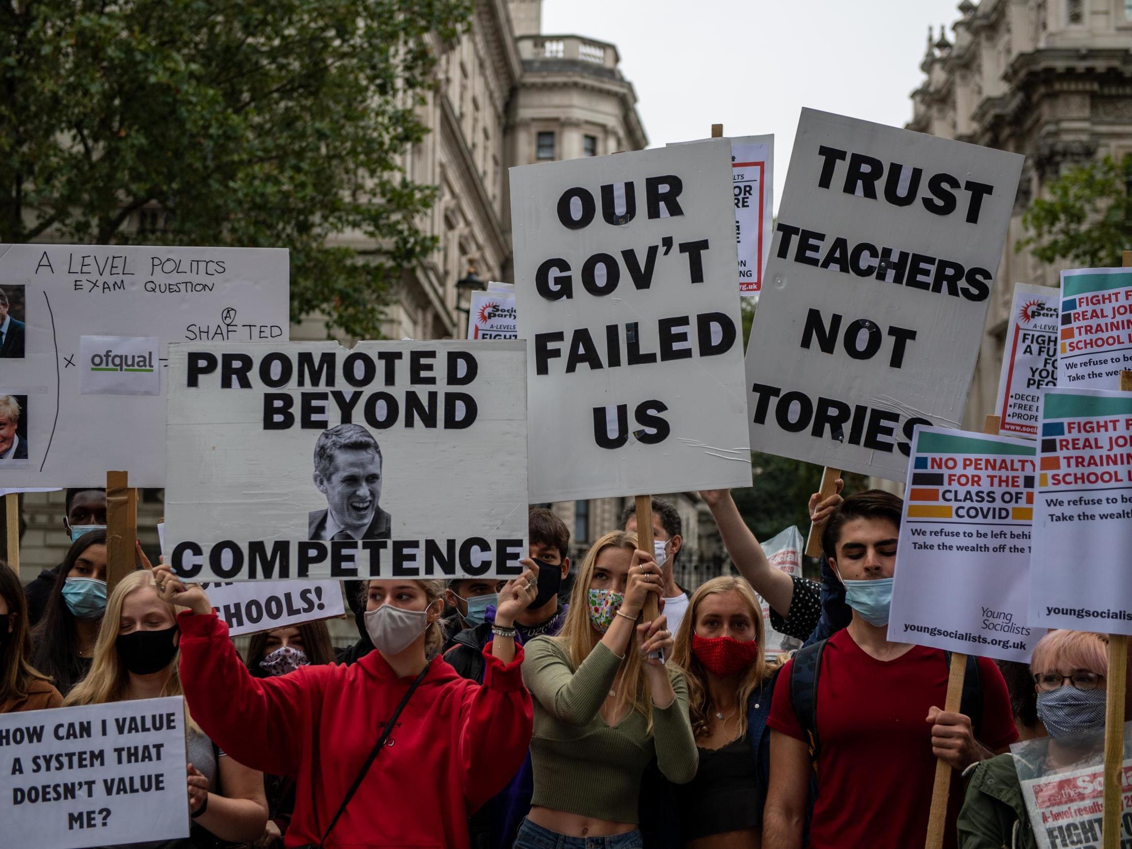 Students, teachers and parents hold placards and wear face masks as they protest against downgraded A level results