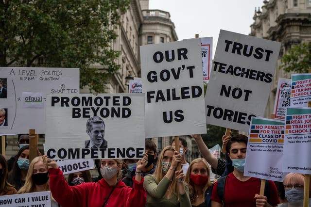 Students, teachers and parents hold placards and wear face masks as they protest against downgraded A level results