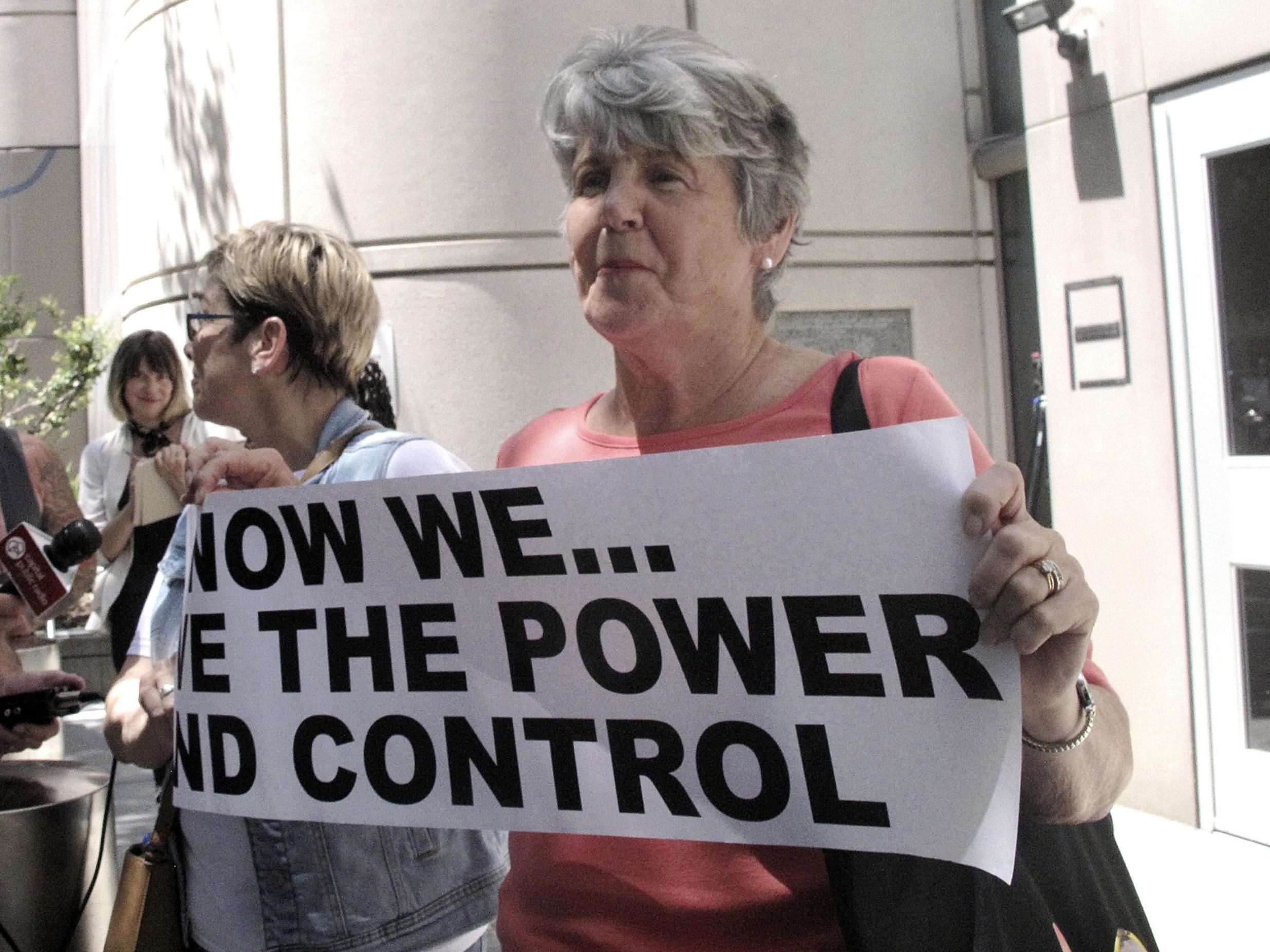 Jane Carson-Sandler, of South Carolina, who was raped by the Golden State Killer in 1976, holds a sign with a message to her attacker in Sacramento, California